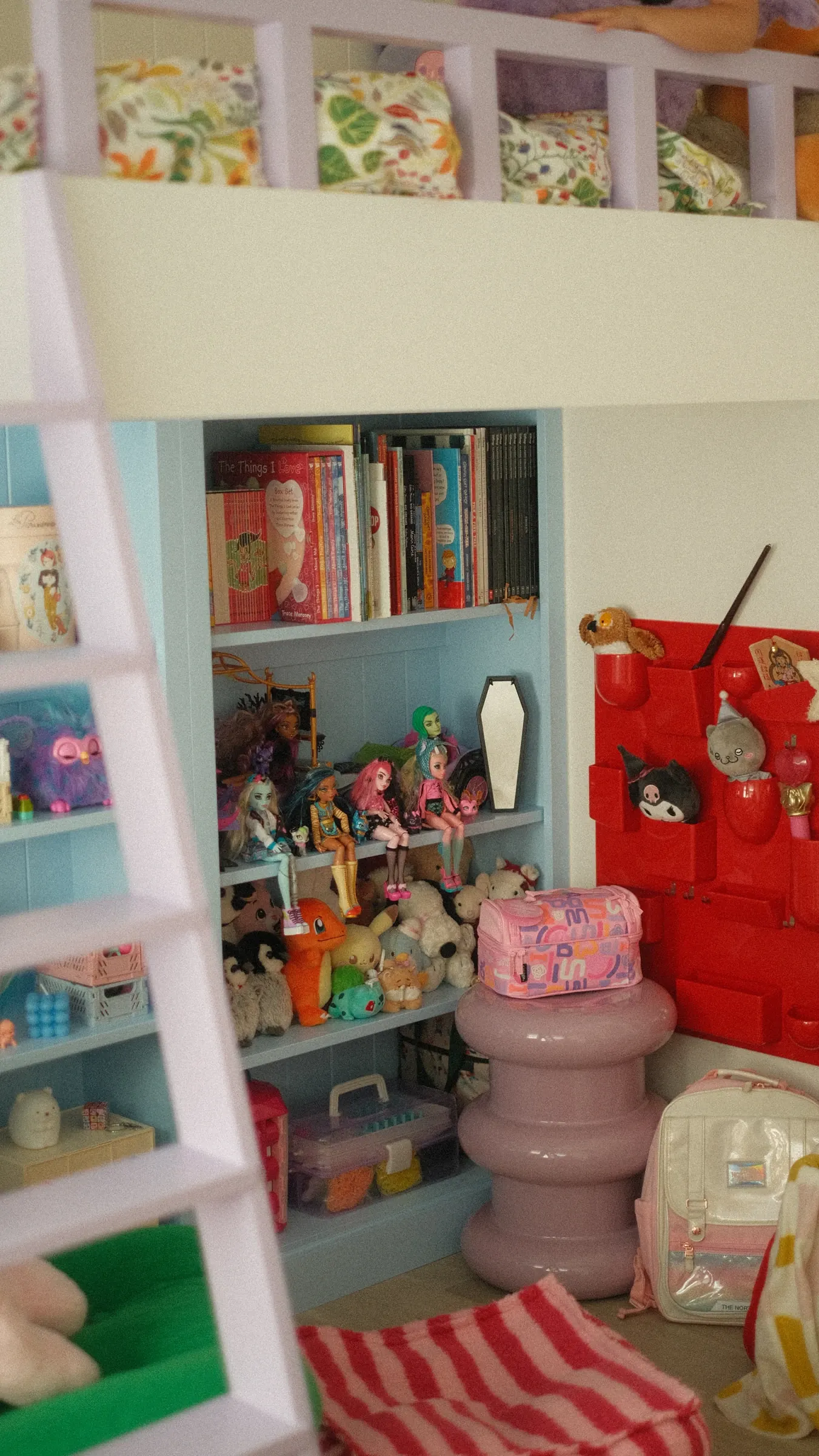 The pastel bunk and blue shelving in Edmond’s daughter’s room, with books, dolls and a pink stool.